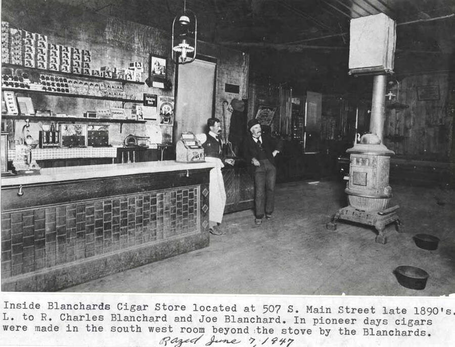 Inside. Located at 507 South Main Street late 1890s. Left to right: Charles Blanchard and Joe Blanchard. In pioneer days cigars were made [by the Blanchard's] in the southwest room beyond the stove. Razed June 7, 1947.