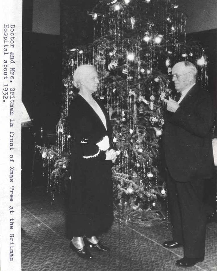 Dr. and Mrs. Gritman stand in front of a Christmas tree in the Gritman Hospital about 1932.