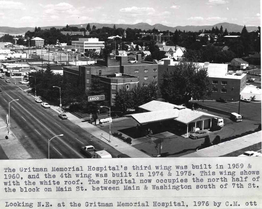 The Gritman Memorial Hospital's third wing was built in 1959 and 1960, and the fourth wing was built in 1974 and 1975. This wing shows with the white roof. The hospital now occupies the north half of the block on Main Street between Main and Washington streets south of Seventh Street. Looking northeast at Gritman Memorial Hospital, 1976 by Clifford M. Ott