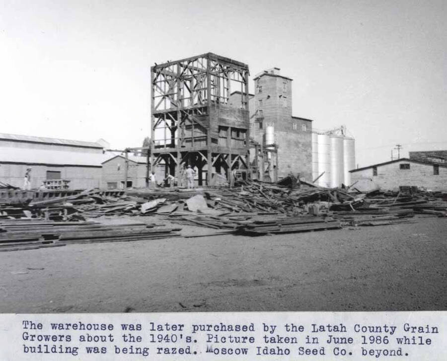 The warehouse was later purchased by the Latah County Grain Growers about the 1940s. Picture taken in June 1986 while building was being razed. Moscow Idaho Seed Company beyond.