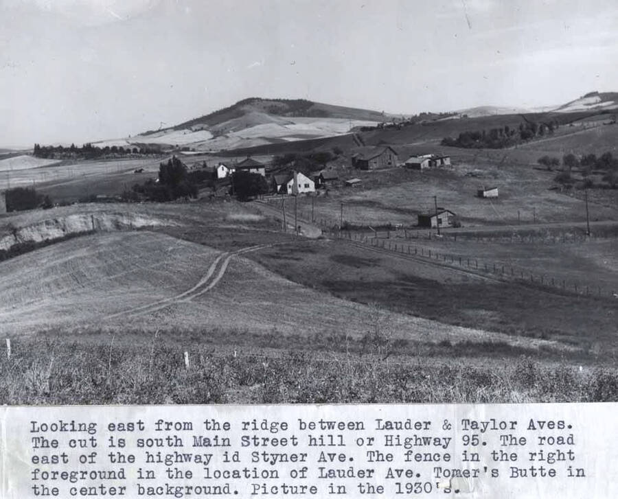 The cut is south Main Street hill or Highway 95. The road east of the highway is Styner Avenue. The fence in the right foreground is the location of Lauder Avenue. Tomers Butte in the center background. Picture in the 1930s.