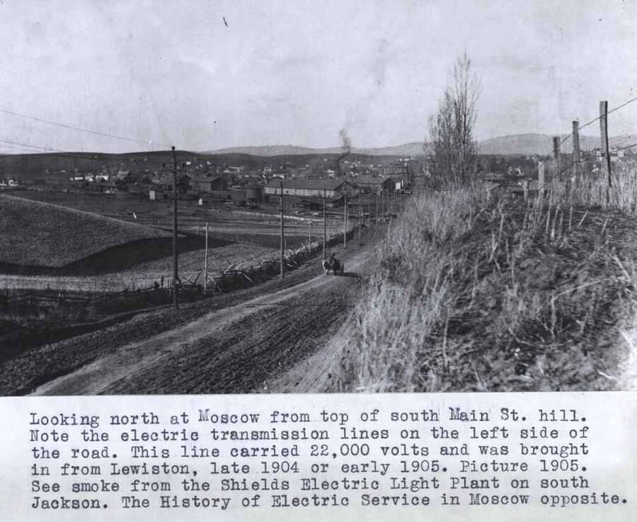 From top of south Main Street hill. Note the electric transmission lines on the left side of the road. This line carried 22,000 volts and was brought in from Lewiston, late 1904 or early 1905. Picture 1905. See smoke from the Shields electric light plant on south Jackson Street.