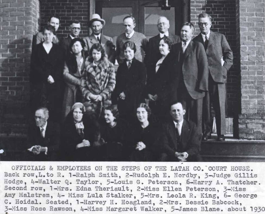 On the steps. Back row, left to right: 1- Ralph Smith, 2- Rudolph E. Nordby, 3- Judge Gillis Hodge, 4- Walter Q. Taylor, 5- Louis G. Peterson, 6- Harry A. Thatcher. Second row, [left to right;] 1- Mrs. Edna Theriault, 2- Miss Ellen Peterson, 3- Miss Amy Malstrom, 4- Miss Lula Stalker, 5- Mrs. Leola R. King, 6- George C. Hoidal. Seated, [left to right:] 1- Harvey H. Hoagland, 2- Mrs. Bessie Babcock, 3- Miss Rose Rawson, 4- Miss Margaret Walker, 5- James  Blane. About 1930