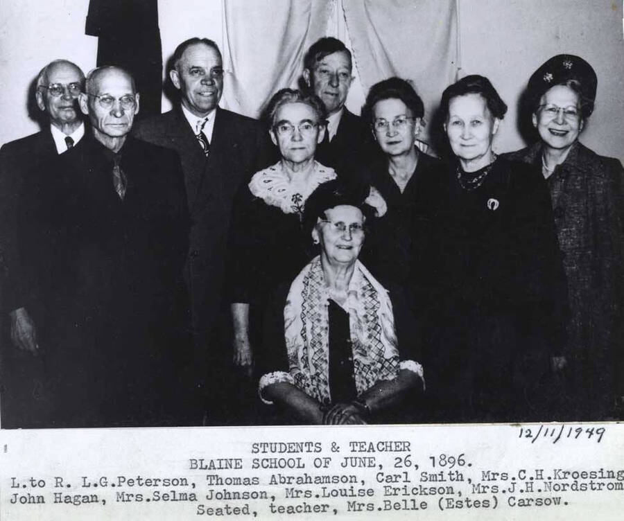 June 26, 1896. Left to right: L.G. Peterson, Thomas Abrahamson, Carol Smith, Mrs. C.H. Kroesing, John Hagan, Mrs. Selma Johnson, Mrs. Louise Erickson, Mrs. J.H. Nordstrom. Seated, [left to right:] teacher, Mrs. Belle (Estes) Carssow. 12/11/1949