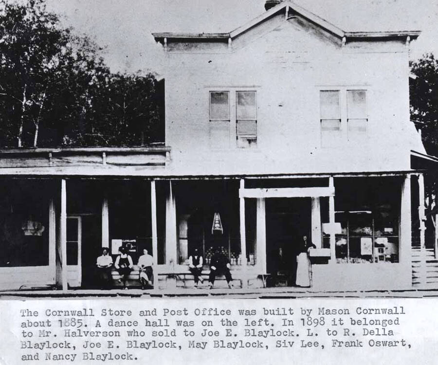 Was built by Mason Cornwall about 1885. A dance hall was on the left. In 1898 it belonged to Mr. Halverson who sold to Joe E. Blaylock. Left to right: Della Blaylock, Joe E. Blaylock, May Blaylock, Siv Lee, Frank Oswart, and Nancy Blaylock.