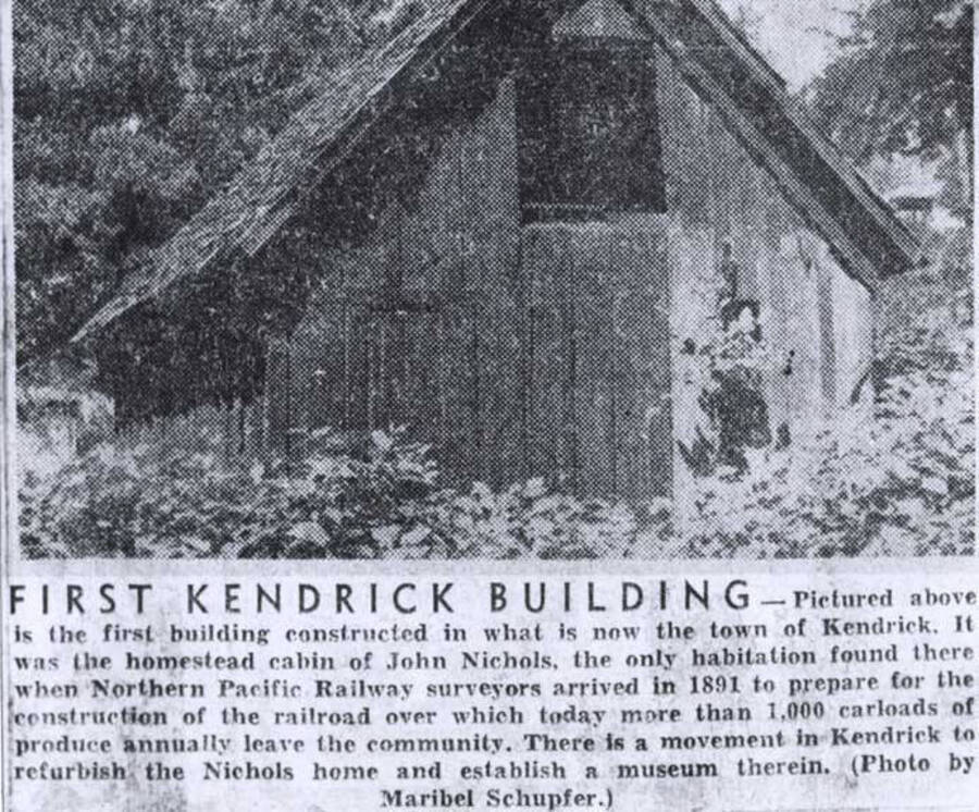 Photo caption wording: "First Kendrick Building. Pictured above is the first building constructed in what is now the town of Kendrick. It was the homestead cabin of John Nichols, the only habitation found there when Northern Pacific Railroad surveyors arrived in 1891 to prepare for the construction of the railroad over which today more than 1,000 carloads of produce annually leave the community. There is a movement in Kendrick to refurbish the Nichols home and establish a museum therein. (Photo by Maribel Schupfer.)".