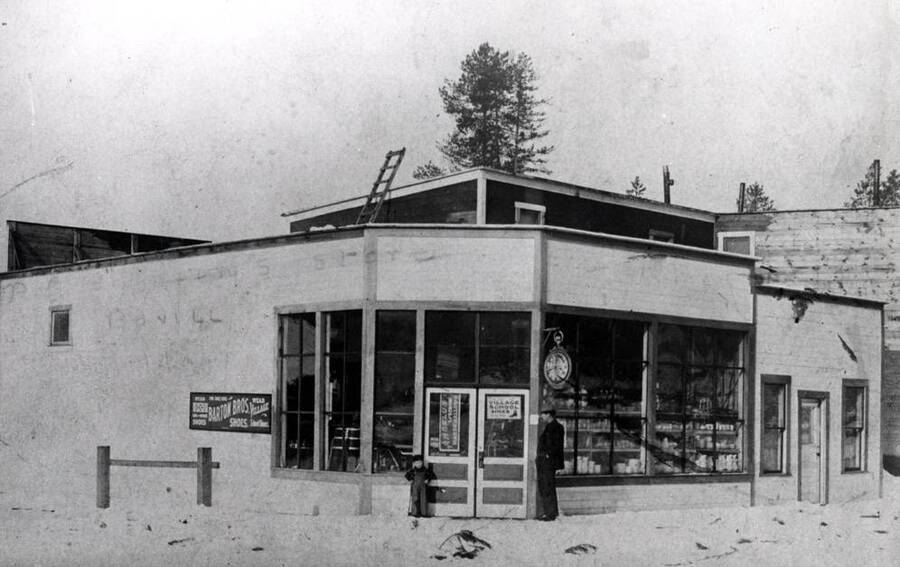First mercantile store in Bovill was located on Second Avenue off Pine Street and owned by Peter Johnson standing at right of door and his small son Hjalmer at the left of doorway to store.