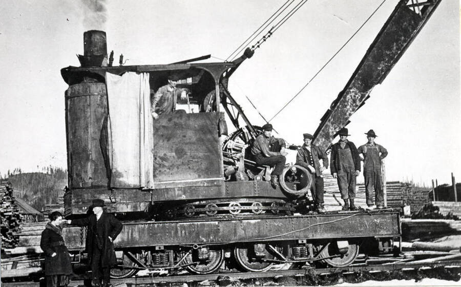 Rig number one, a steam engine-powered derrick for handling cedar poles in the yards at Bovill. Bill Melow (operator), Fred Waller, Wanke Heidke, and Betty Helmer, left in picture. Others not named.