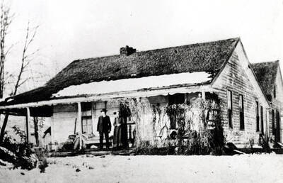 William and Priscilla Taylor on the porch of the house built by him and in which he died at the age of 91 in 1911. They homesteaded in 1871 and first lived in a log cabin on the north bank of the South Palouse [River] and built the above [90-7-004] house in the 1890s, about one block west of the crossroads south of town on the north side of road east of the Latah County Convalescent Center.