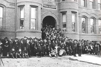 [Members of] G.A.R. Anderson Post #14 in front of high school. Col. Robert H. Barton in front with sabre standing at attention. Picture 1890s.