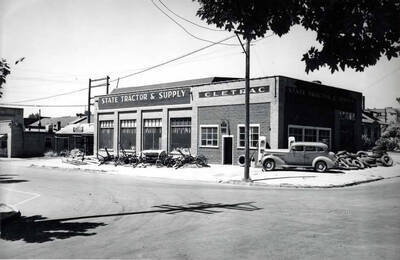 Northwest corner of Sixth and Washington streets. Driveway through the corner near gas pumps closed. State Tractor, farm equipment. Late 1930s or 1940s.