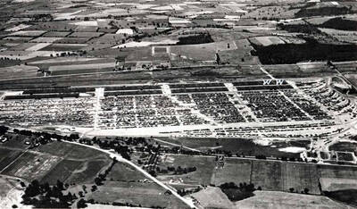 Looking west at the government holding point showing the two sections leased by Washburn-Wilson Seed Company. Later the section at the end of the building was sub-leased to the Corning Glass Company where they stored television picture tubes. Washburn-Wilson Seed Company was in the other section where the packaging equipment was installed and sacked beans on pallets stored. Each section was 180 feet wide and 240 feet long. Office was in the end section. Holding point was used by the Army during World War II.