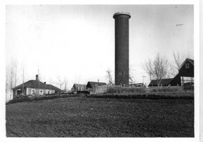 Old Standpipe (water tank) was built in 1889 and razed in 1931 or 1932. Located in the center of the block north of A Street in line with East B Street between Jefferson and Adams streets. TFrst piped well water came in 1889 with a $30,000.00 bond issue. House at left is located at 226 North Jefferson [Street]. Picture by M.L. Romig about 1907.