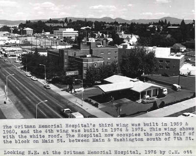 The Gritman Memorial Hospital's third wing was built in 1959 and 1960, and the fourth wing was built in 1974 and 1975. This wing shows with the white roof. The hospital now occupies the north half of the block on Main Street between Main and Washington streets south of Seventh Street. Looking northeast at Gritman Memorial Hospital, 1976 by Clifford M. Ott
