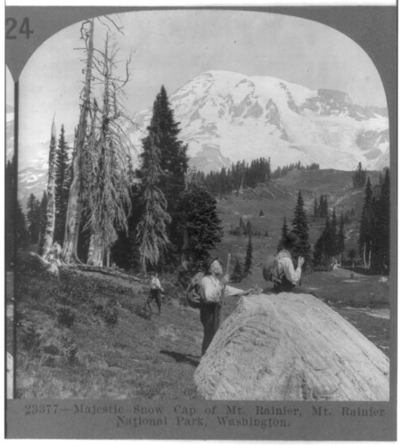 Black-and-white stereograph print of the snow capped summit of Mount Rainier showing three men at the far base of the mountain.