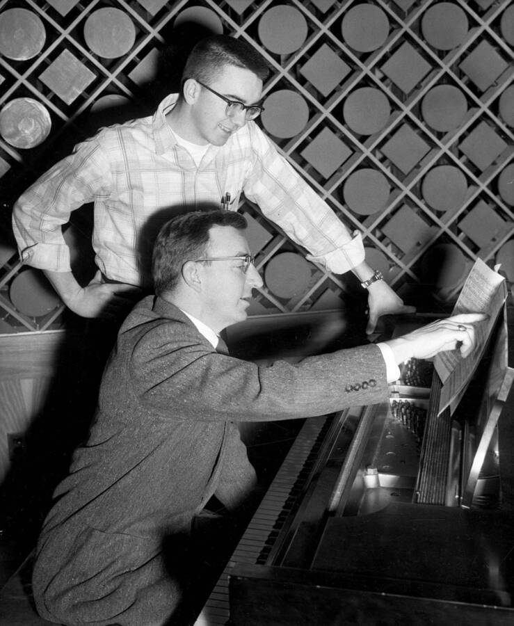Glen Lockery sitting at a piano and  Neil Sampson looking over his shoulder.