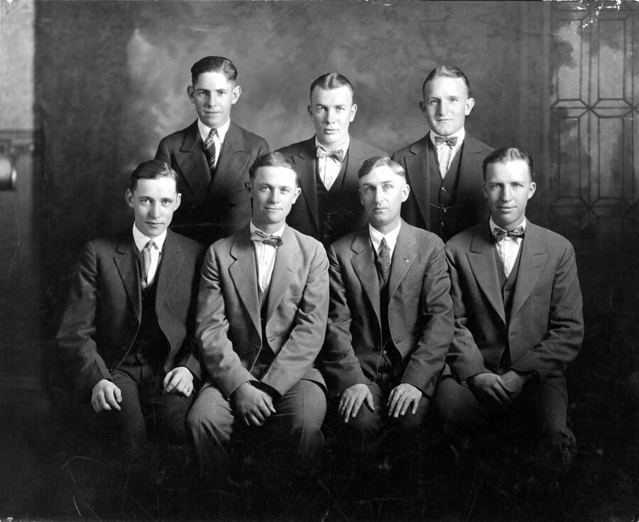 Members of the stock judging team pose for a formal portrait. Individuals identified from top left to right: Dan Warren, Dave Foles, Willard Lamphere. Individuals identified from bottom left to right: Ralph Stucky, Neil Derrick (alternate), Coach C.W. Hickman, L.J. Peterson. The photographer was D. Perry Evans
