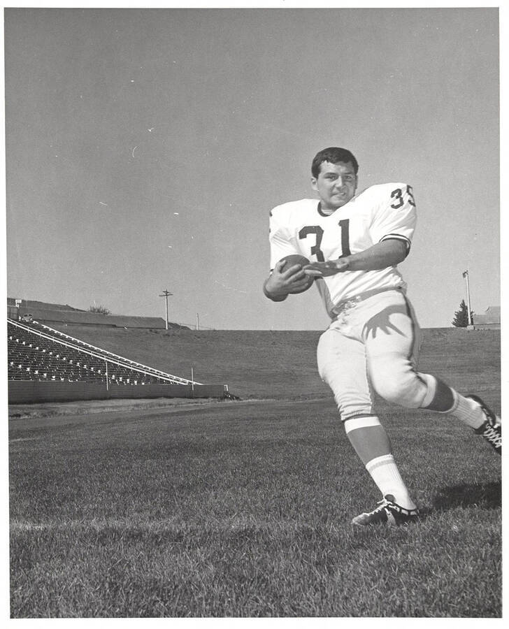 Running back, Mike Wiscombe, running in front of the stands with a football.