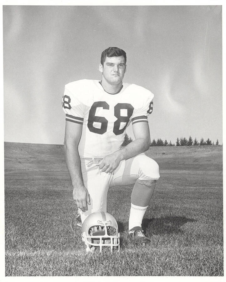Jim Wimer, an offensive guard for the University of Idaho, kneeling by his helmet.