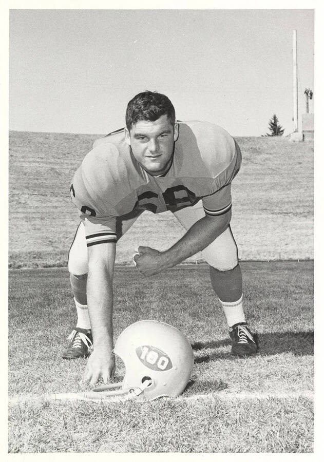 Jim Wimer, an offensive guard for the University of Idaho, crouching over his helmet for the photo.