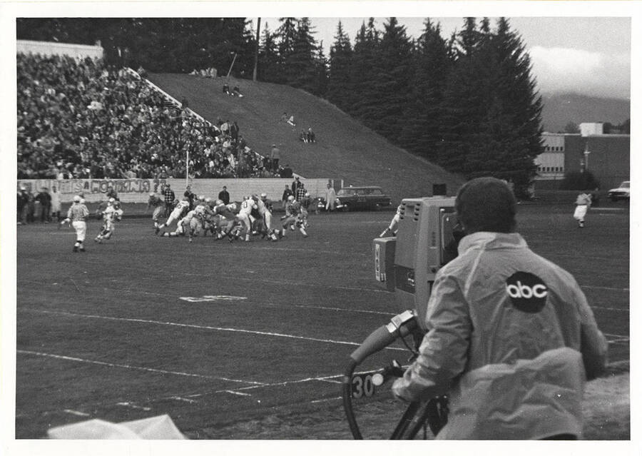 ABC television cameraman on the sidelines filming a tackle during a University of Idaho football game.