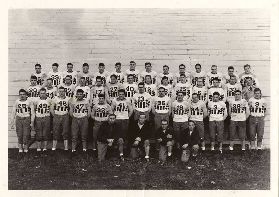 A photo of the University of Idaho football team with their coach Ted Bank in front of the bleachers.