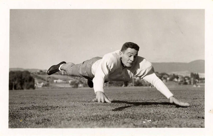 An action shot of Glenn Rathbun, a tackle for the University of Idaho football team, hovering over the field before he lands.