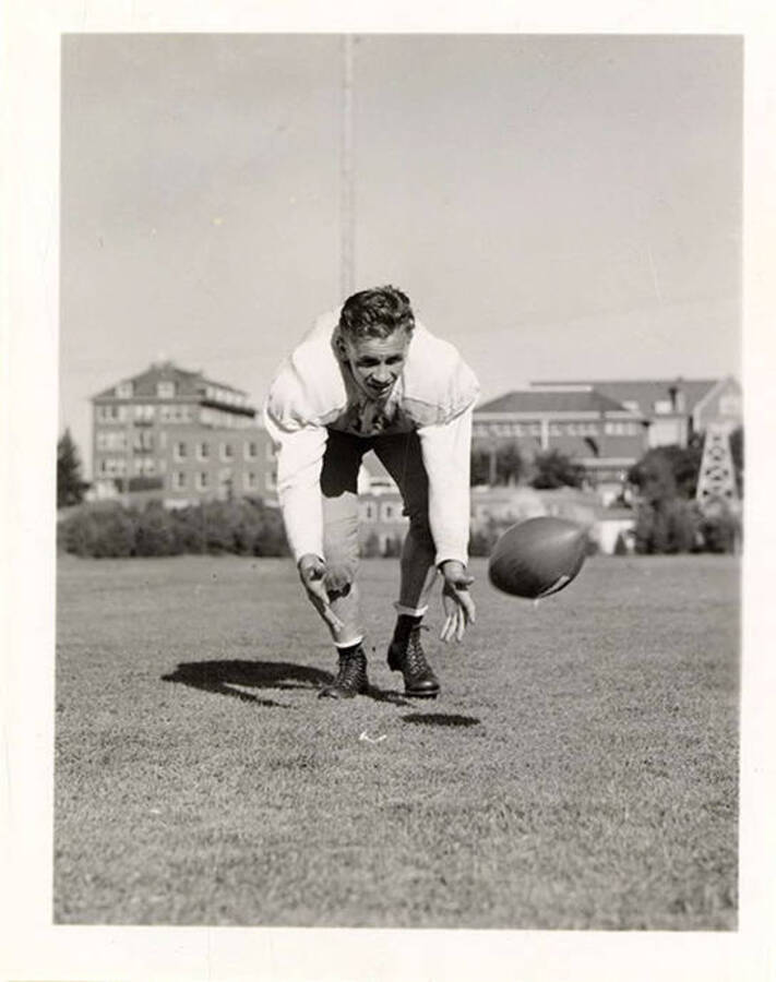 Charles LeRoy Atkinson, left halfback for the University of Idaho football team, catching a football.
