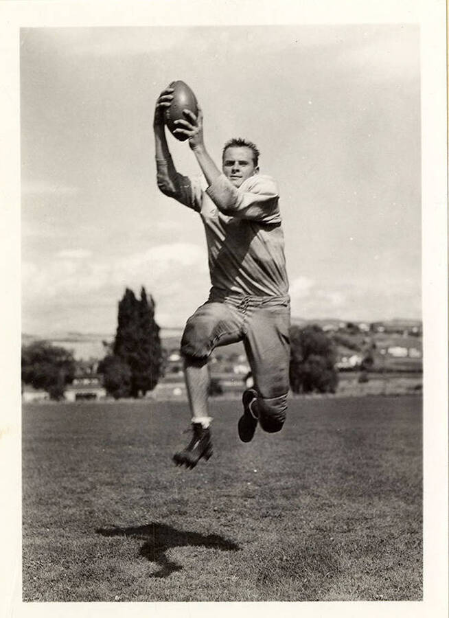 Veto Berllus, right end for the University of Idaho football team, catching a football mid-air.
