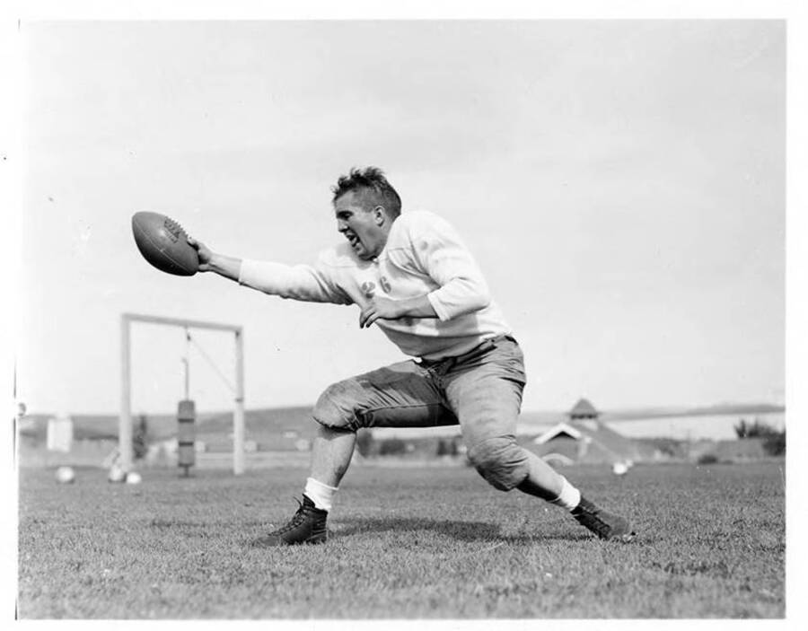 Chester Long, quarterback for the University of Idaho football team, taking an action shot in front of some football equipment on the field.