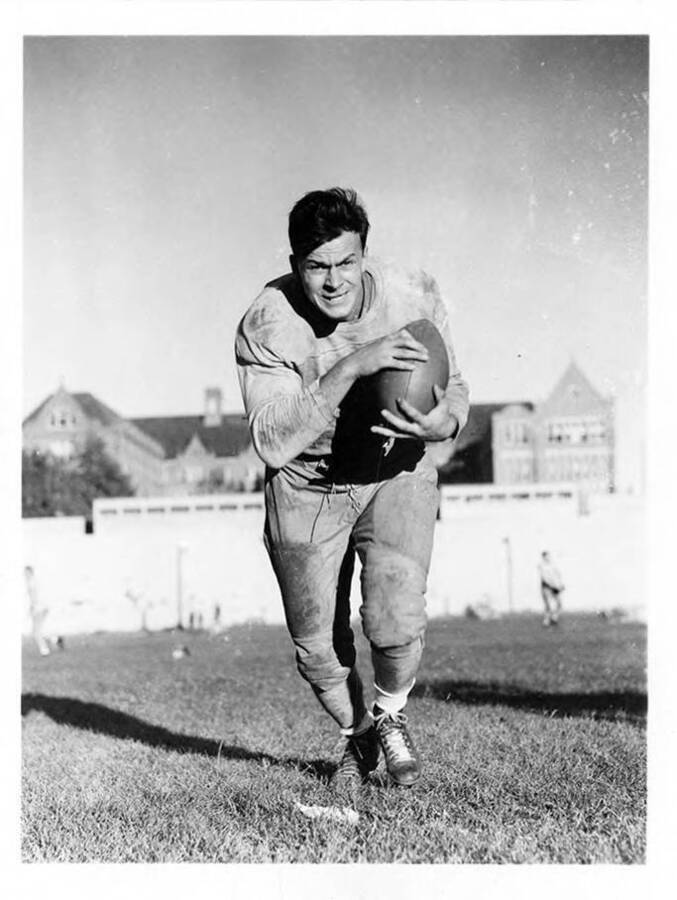 Fullback for the University of Idaho football team, William Micklich, running towards the camera with a football.