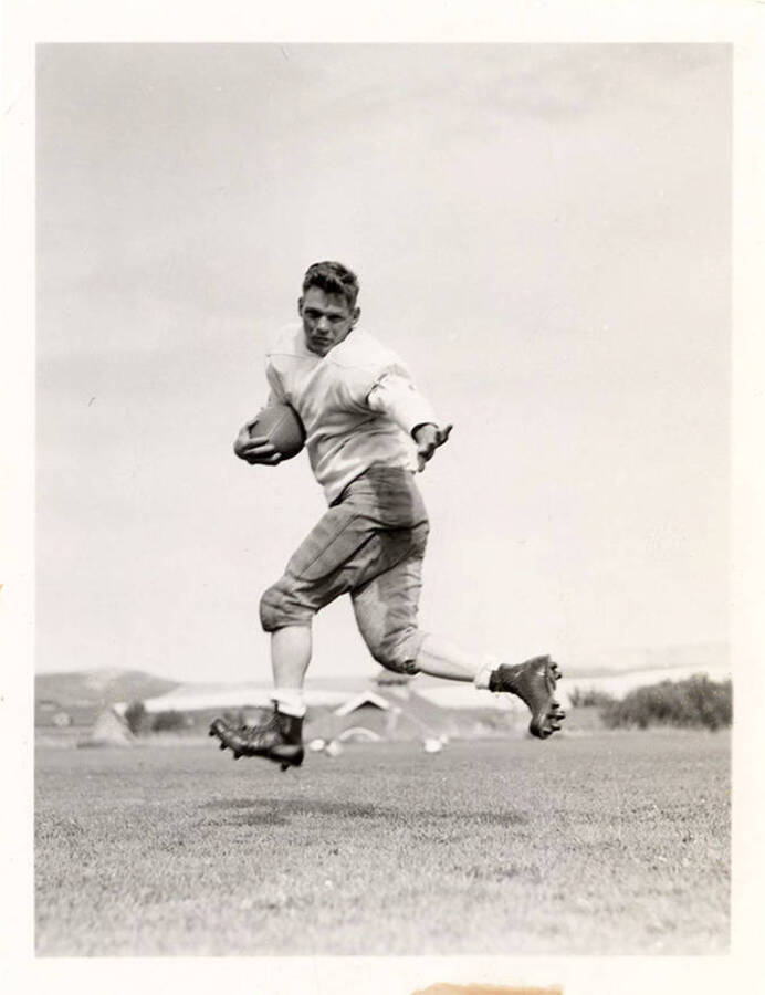 Bob Smith, halfback for the University of Idaho football team, mid-air with a football.