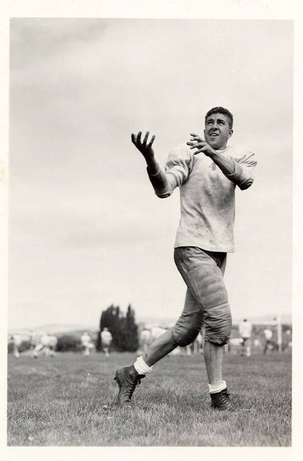 George Whitlock, football player for the University of Idaho, catching the ball during practice on the field.