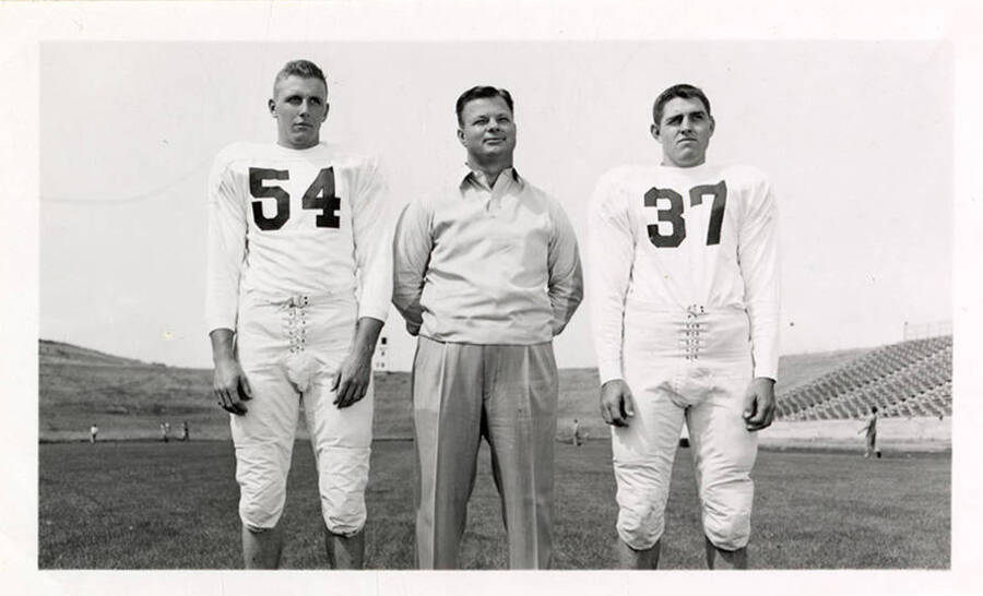 Two freshman football players, Don Wisdom (#54) and Darrell Surber (#37) standing with Coach 'Babe' Curfman.
