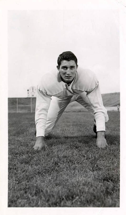 Freshman football player for the University of Idaho, Ed Barton, crouching on the field.