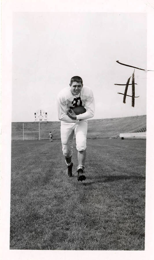 Freshman football player, Darrell Surber (#37), running towards the camera with a football on the University of Idaho field.