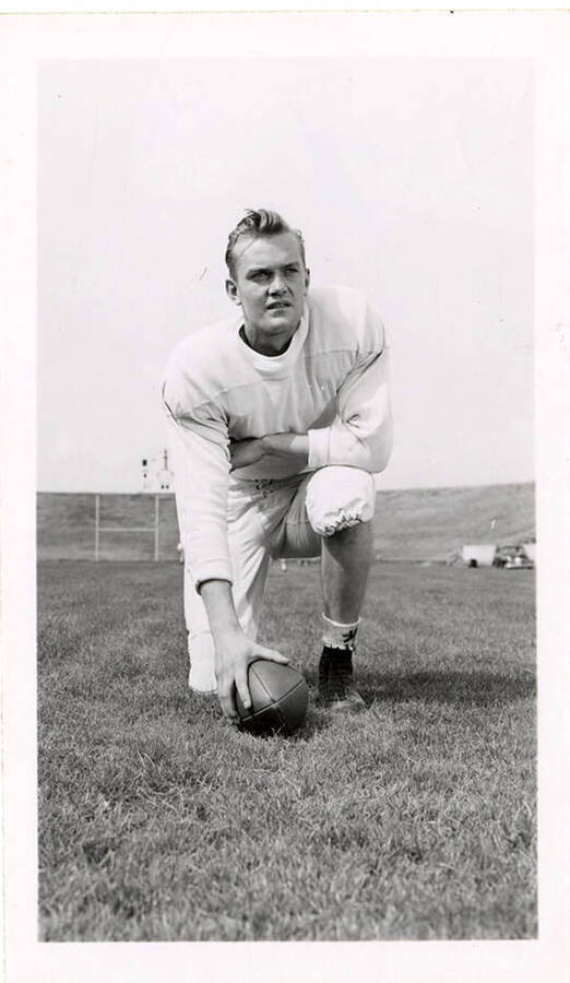 University of Idaho freshman football player, Tony Tardiff, kneeling with one hand on a football.