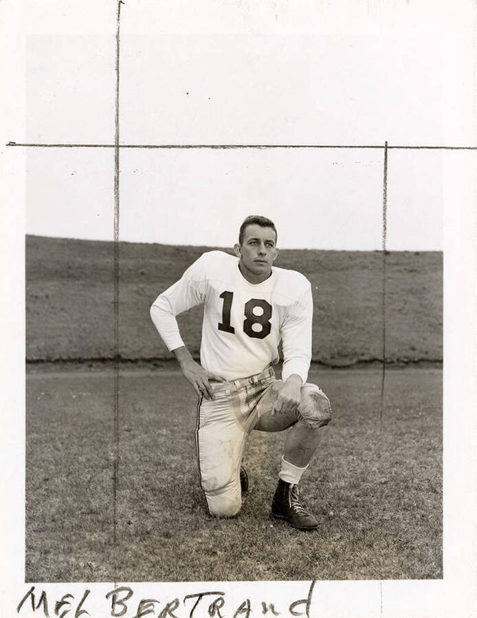 Mel Bertrand (#18), center for the University of Idaho football team, kneeling on the football field.