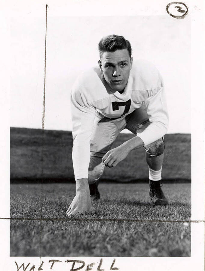 Walt Dell (#7), right halfback for the University of Idaho football team, kneeling on the field.