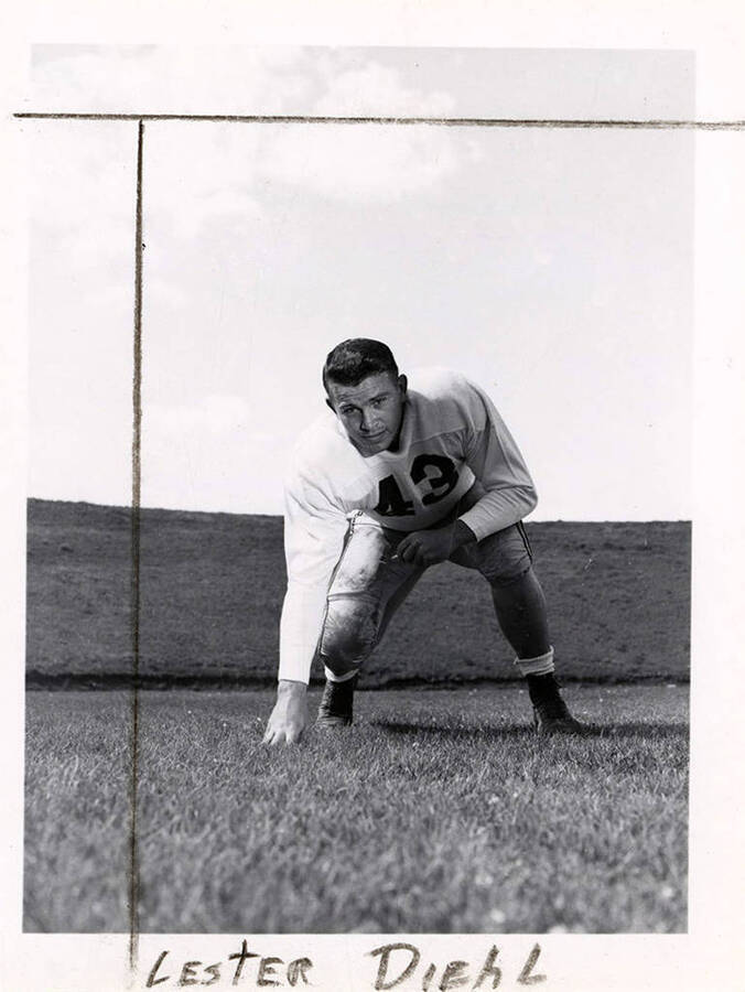 Guard for the University of Idaho football team, Lester Diehl (#43) crouching with a hand on the football field.
