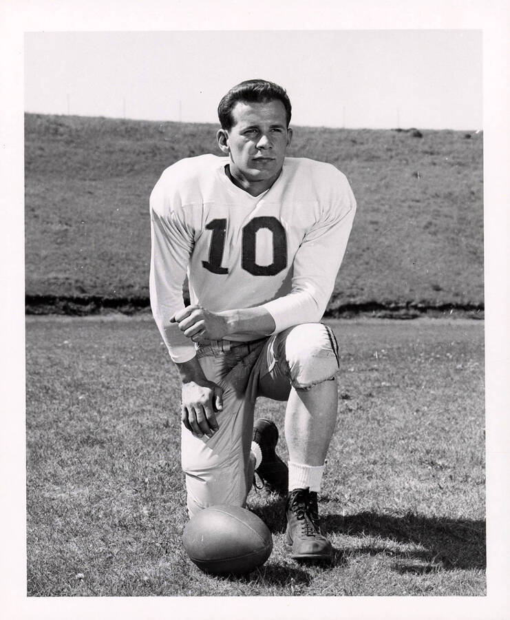 Fullback for the University of Idaho football team, Bud Fisher (#10), kneeling next to a football.