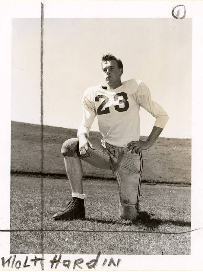 Football player, Walt Hardin (#23), end for the University of Idaho, kneeling on the football field.