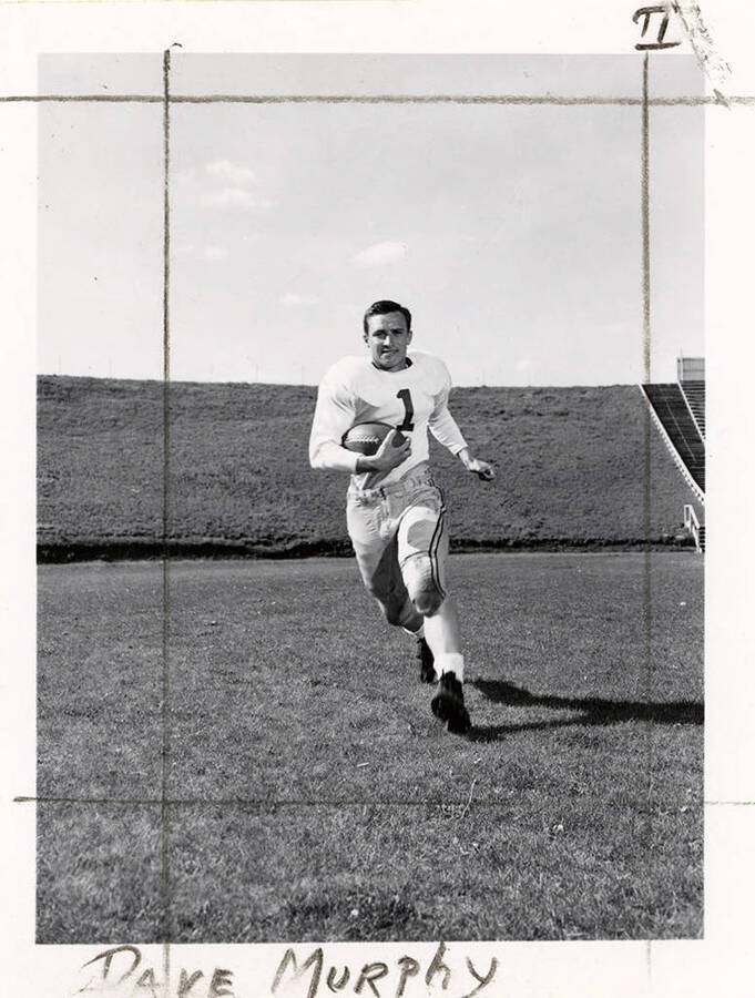 Dave Murphy (#1), right halfback for the University of Idaho football team, running with a football on the field.