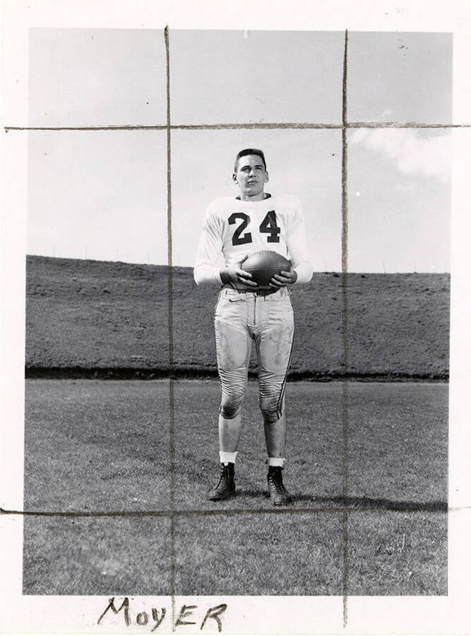 Larry Richard Moyer (#24), end for the University of Idaho football team, standing with a football on the field.