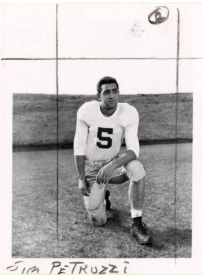 Left halfback for the University of Idaho football team, Jim Petruzzi (#5), kneeling  on the football field.