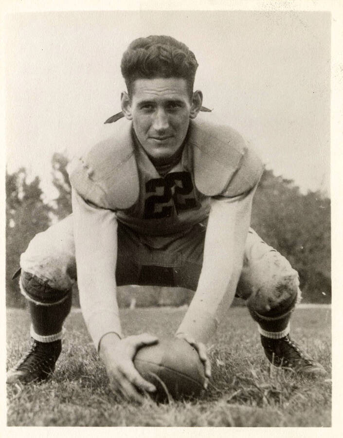 Football player for the University of Idaho, Bob Moore, crouching on the field with a football.