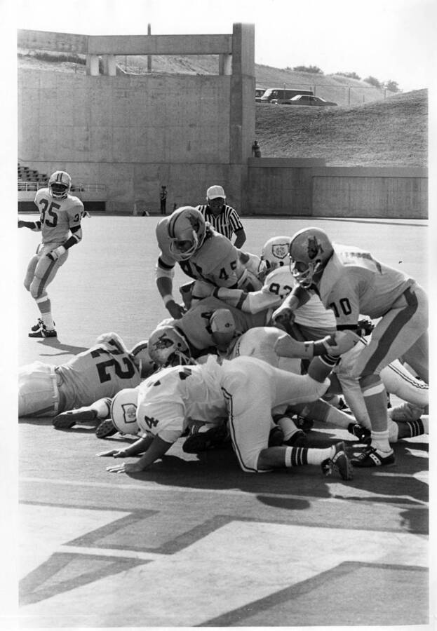 Vandals pile onto the opposing players in a tackle that turned into a dogpile of football players as a referee runs to break it up.
