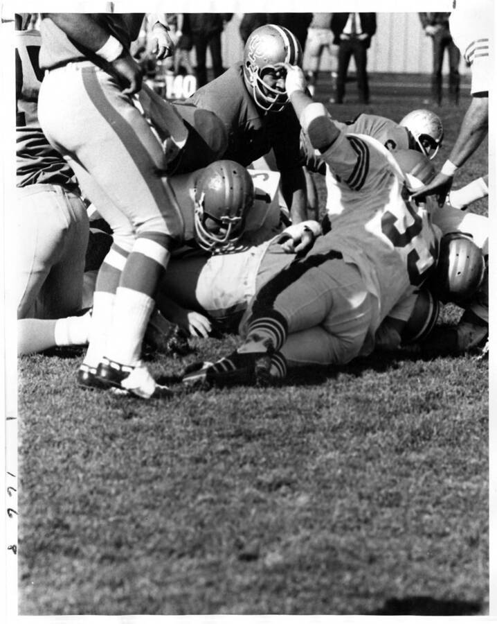 Players are piled into a tackle as others come to help them up.