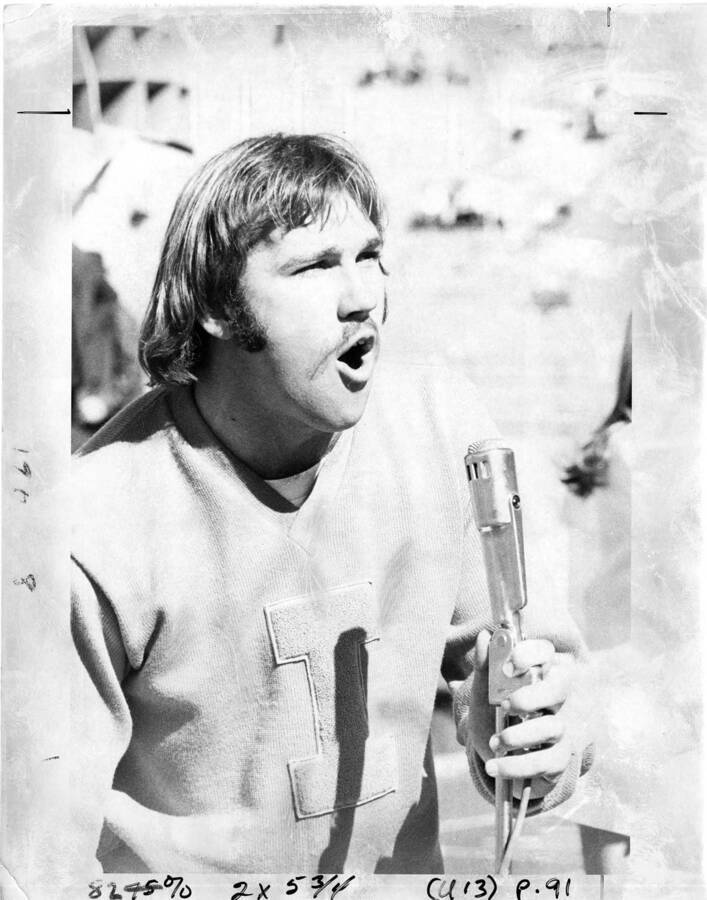 A man wearing University of Idaho apparel speaks into a microphone.