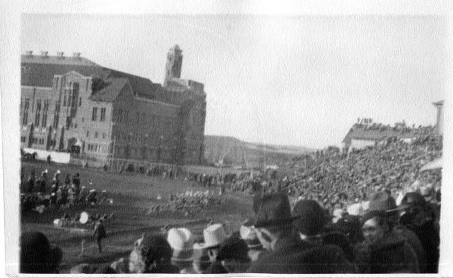 A fuzzy photograph taken from the audience of the football field, surrounding buildings, and packed stands at a University of Idaho football game.